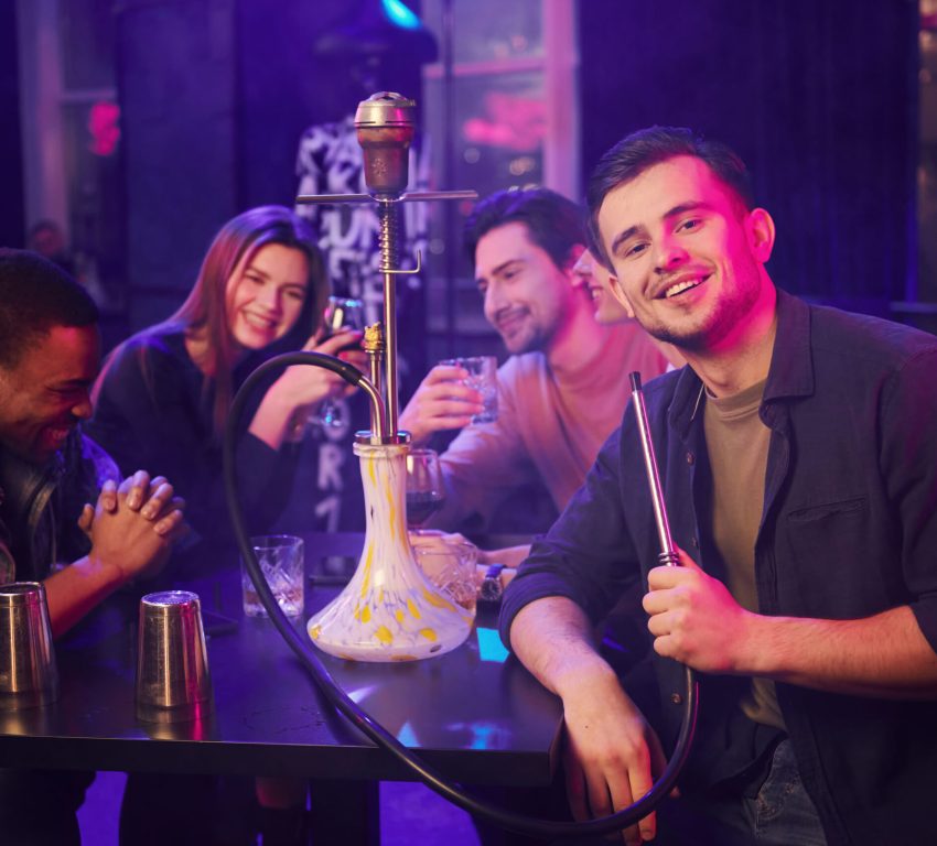 A group of friends having drinks and smoking hookah at a hookah bar.