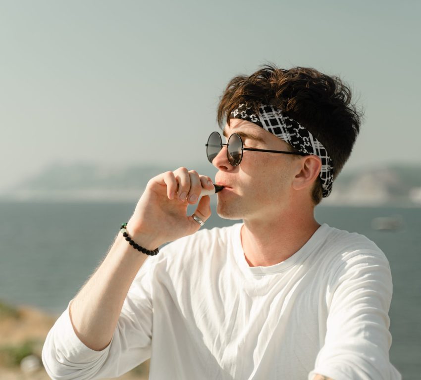 A man wearing a white shirt smoking a vape